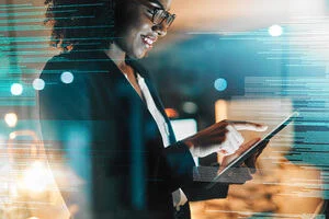 A businesswoman smiles as she taps on her iPad.