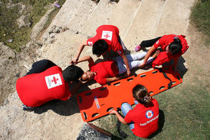 Red Cross First Aid workers help a teenage girl onto a stretcher.