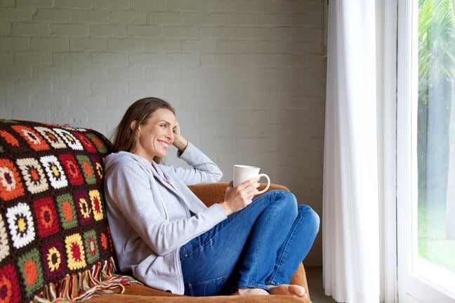 Smiling older woman relaxing at home with cup of tea.