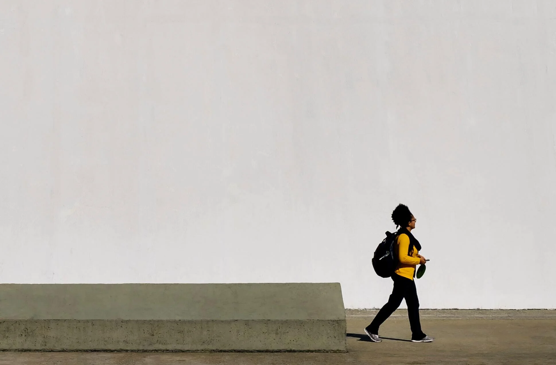 Woman walking, diminished by the large concrete city landscape of walls and paths