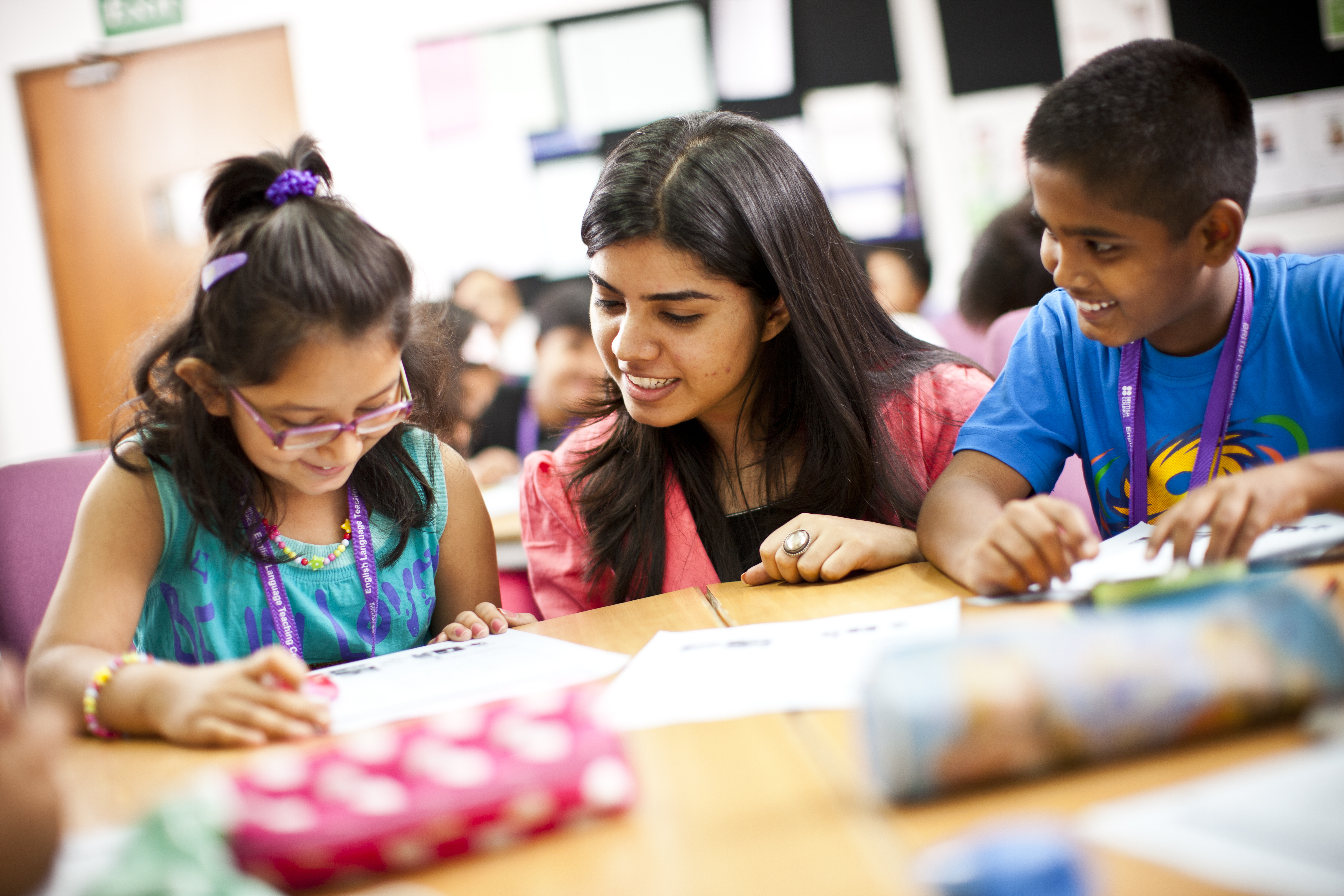 Teacher talking to primary students around a desk.