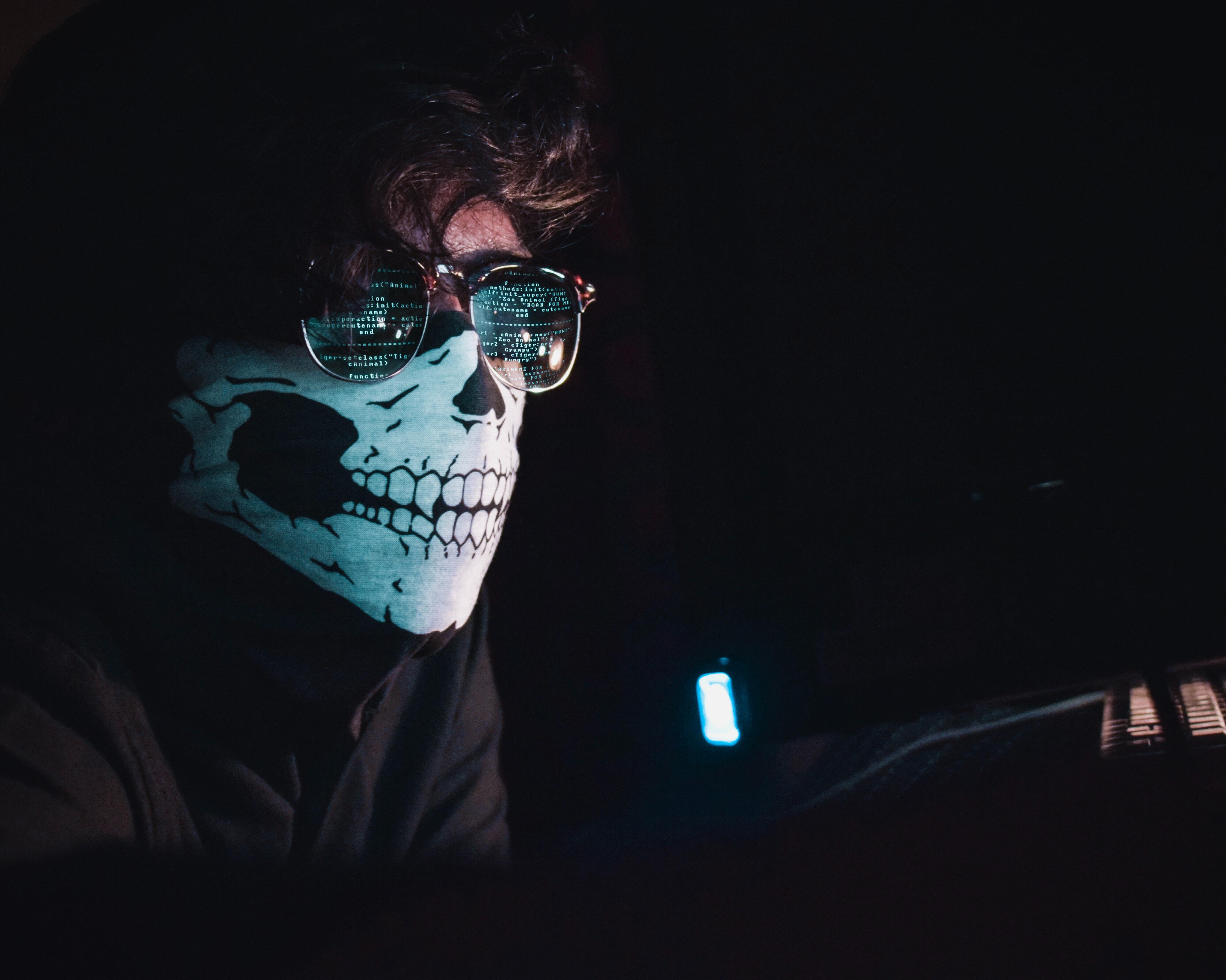 Person in the dark with sunglasses and a skull mask on