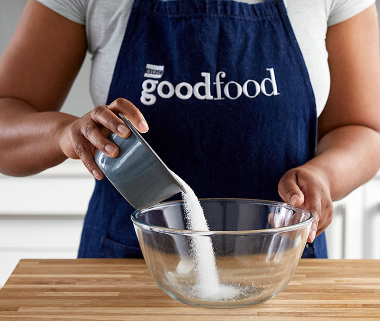 Chef pouring caster sugar in a bowl