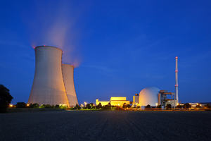The image is of a Nuclear power station at night, two cooling towers are in shot.