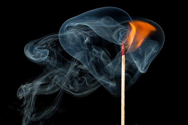 Beautiful whisps of smoke around the burning end of a matchstick