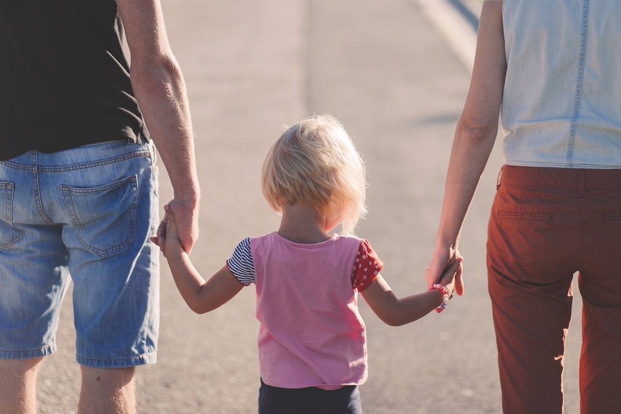 two adults and a child holding hands