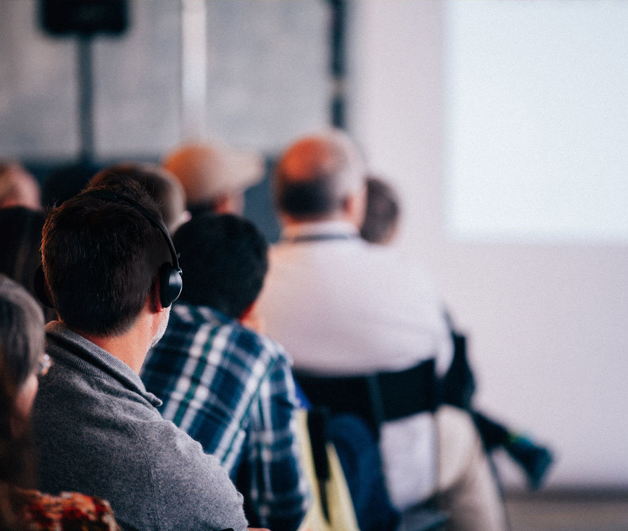 Man listening to lecture through hard of hearing headphones