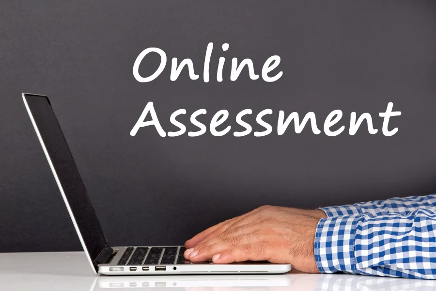 Someone working at a laptop. The words 'online assessment' is beside the laptop.