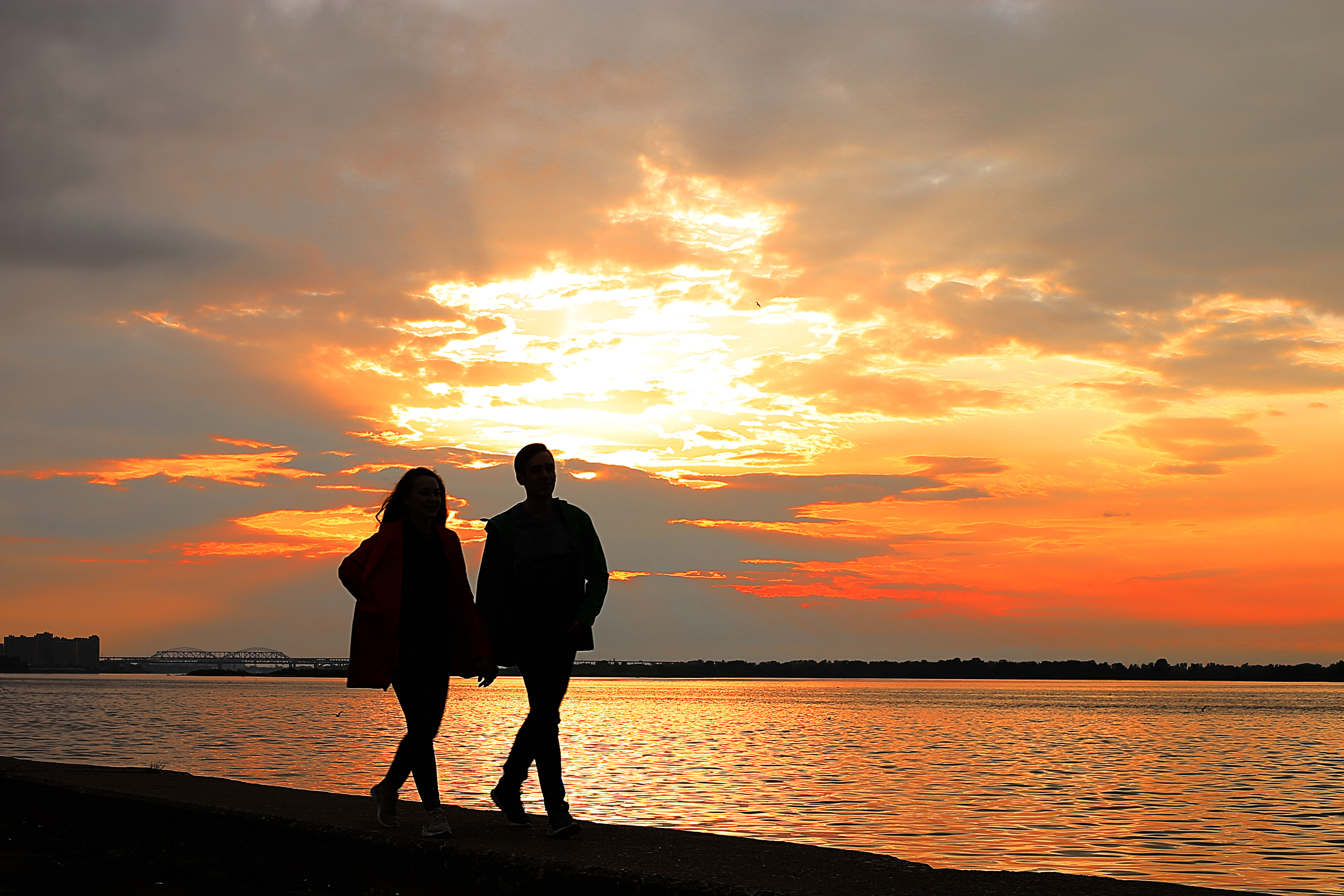 Couple walking on the beach silhouetted by sunset