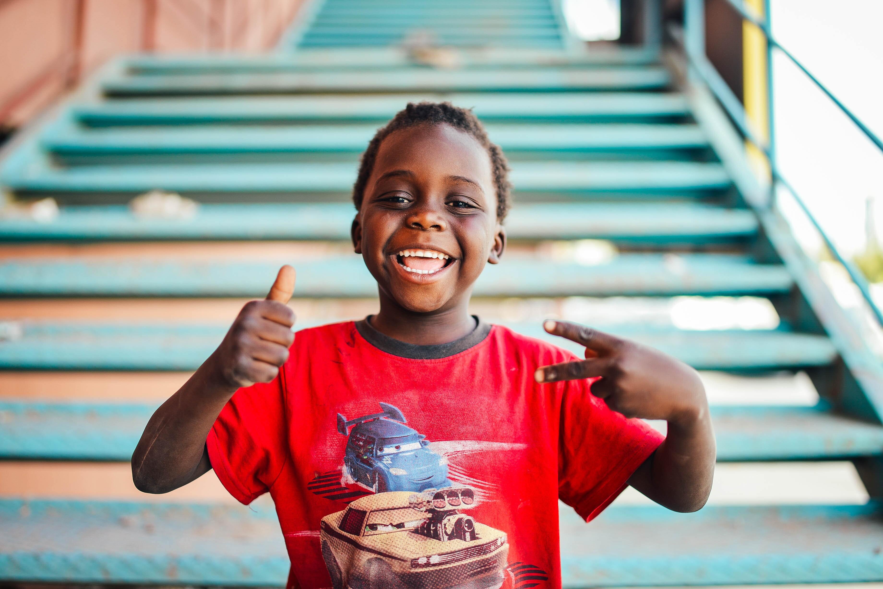 Child giving the camera a thumbs up with a big smile