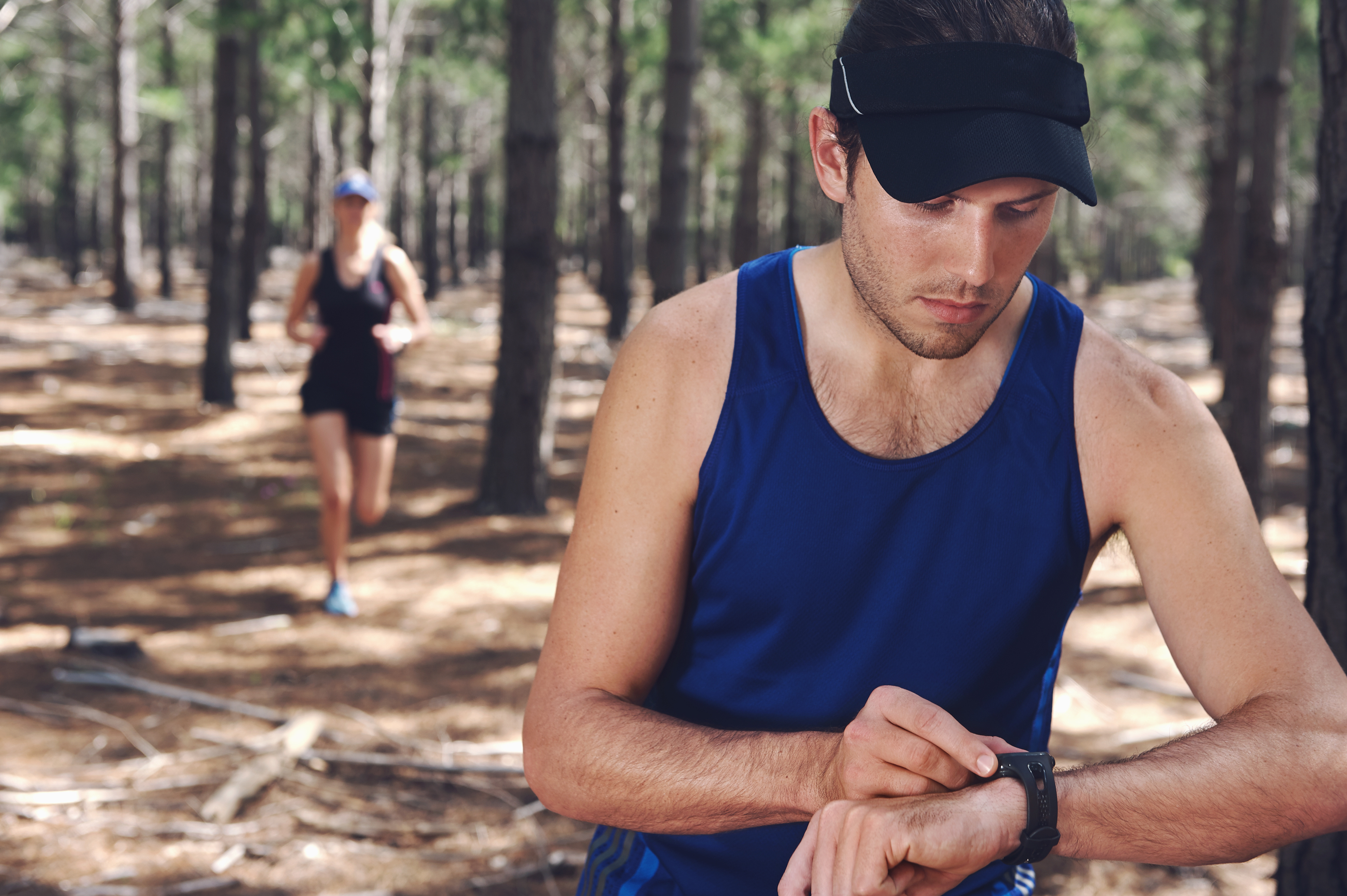 A runner in a forest checks his watch