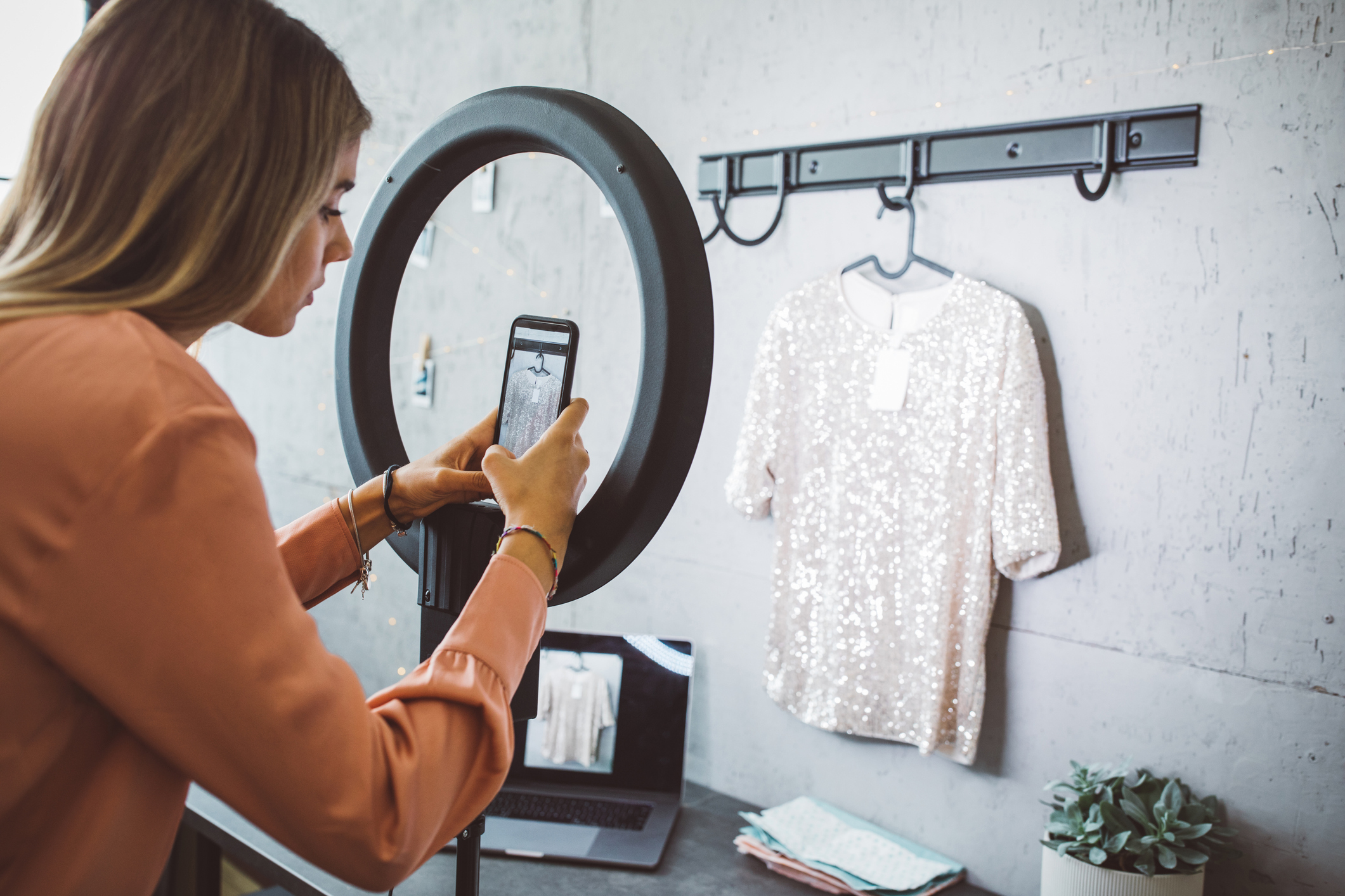 A person taking a photo of a t-shirt hanging on a hanger.