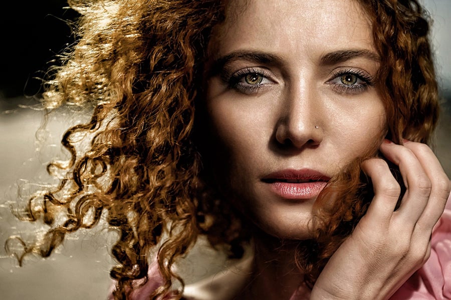 woman with curly hair looking thoughtful and upset