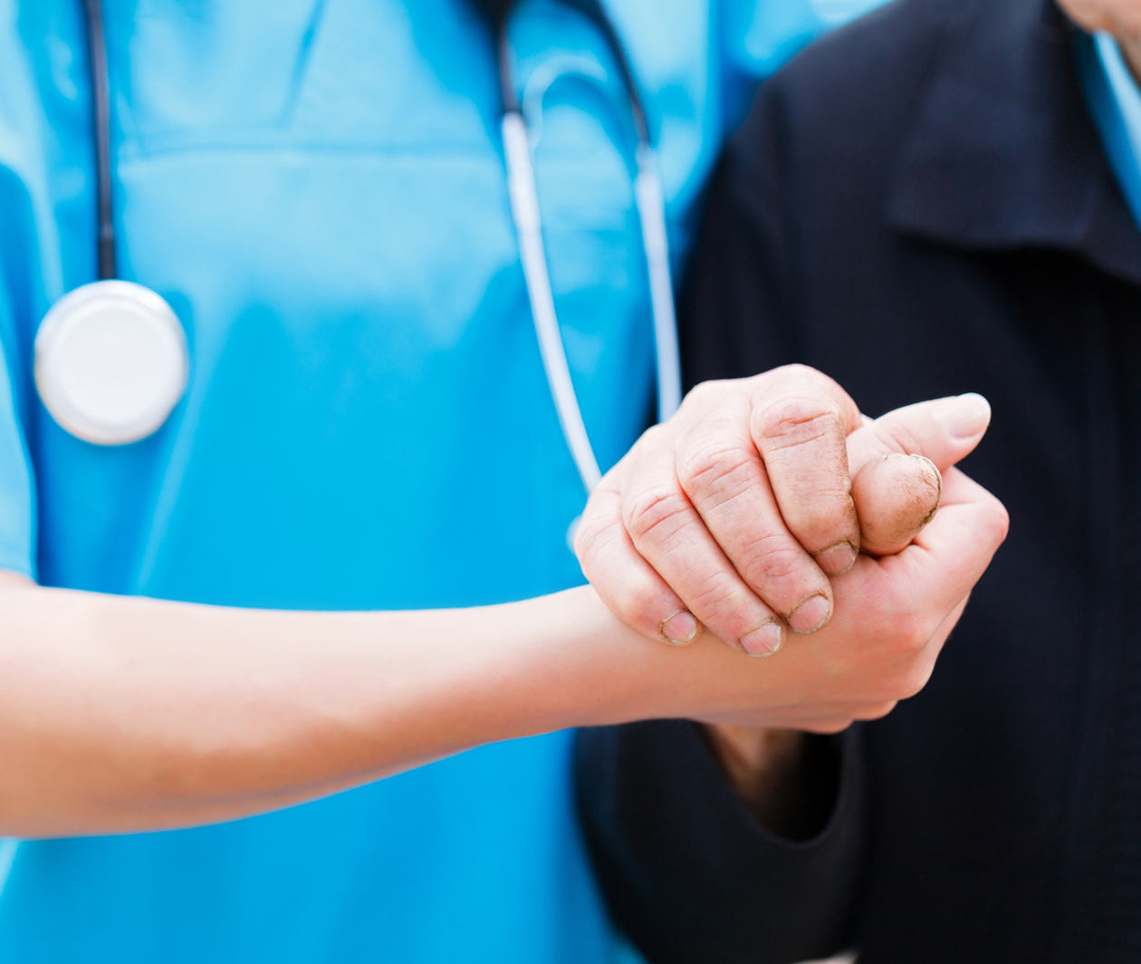 A nurse holding a patient's hand