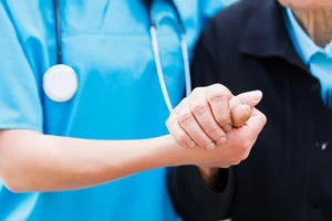 A nurse holding a patient's hand