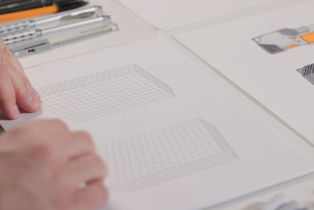 Educator showing two 3D grid templates which will be used for sketching the communications device