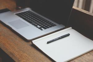 Writing a CV online: a laptop, notebook and pen on a desk