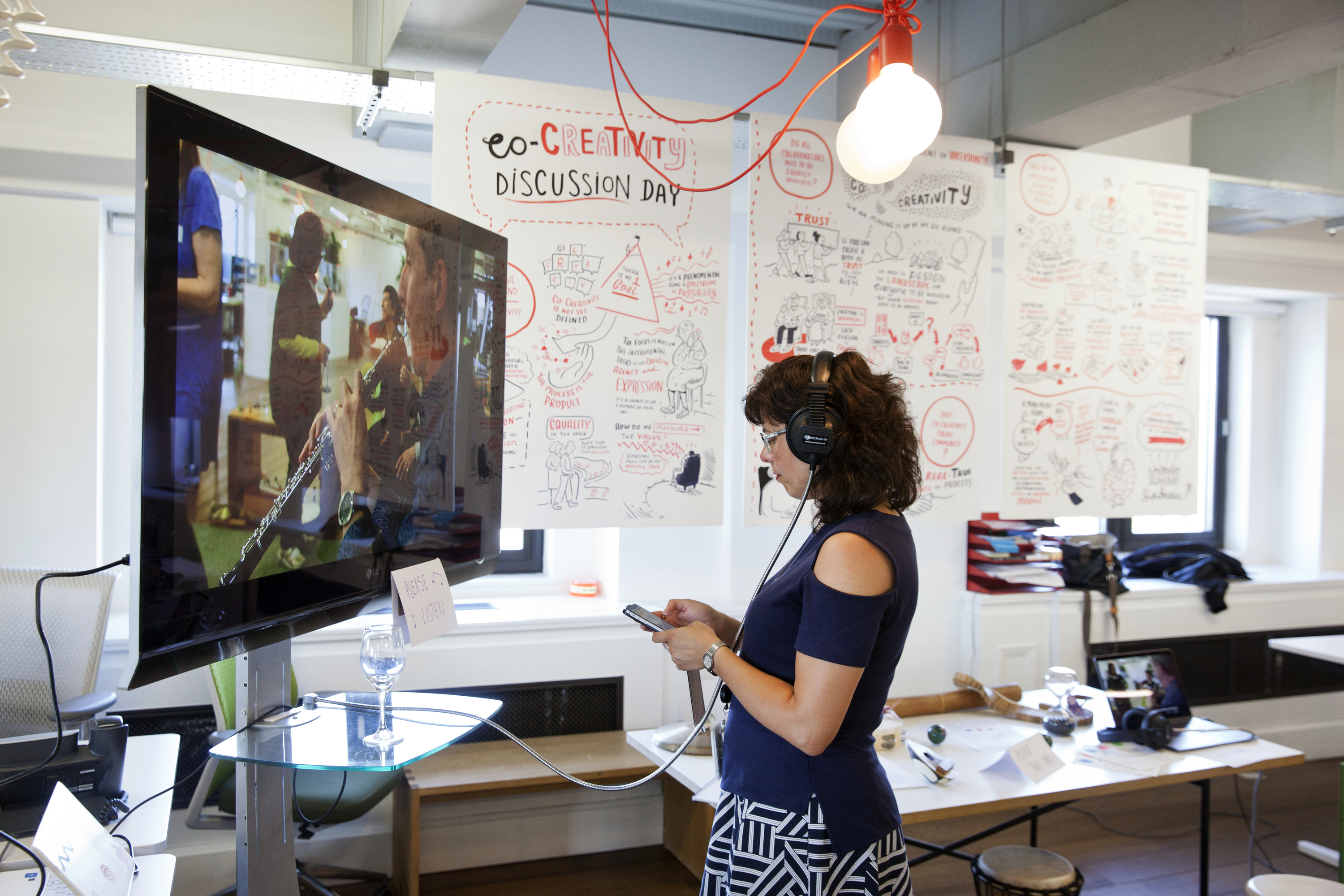 Photograph of a person watching and listening to something on a large TV screen