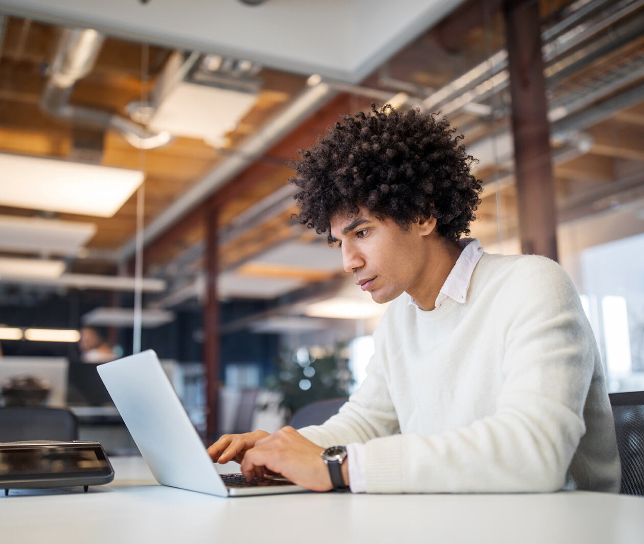 Male professional sitting at conference table working on laptop computer.