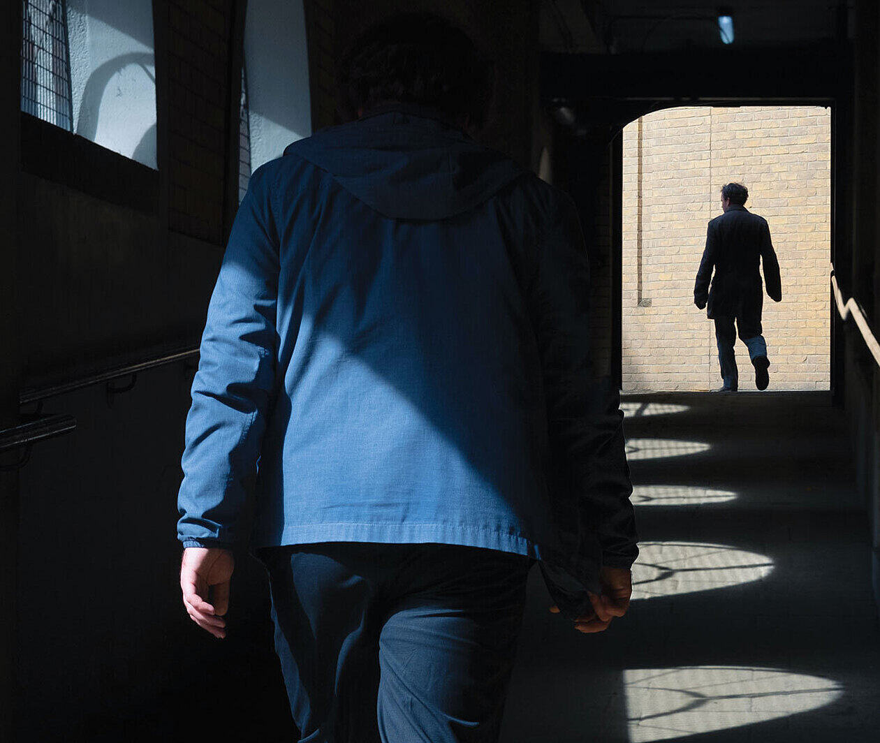 Person following someone down a poorly lit hallway