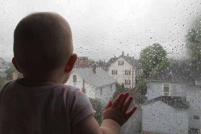 Child staring out of window at rain