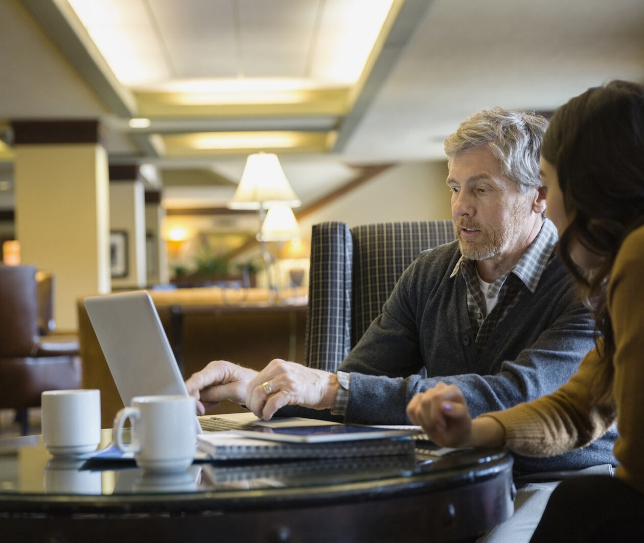 Businessman and businesswoman working at laptop in lobby