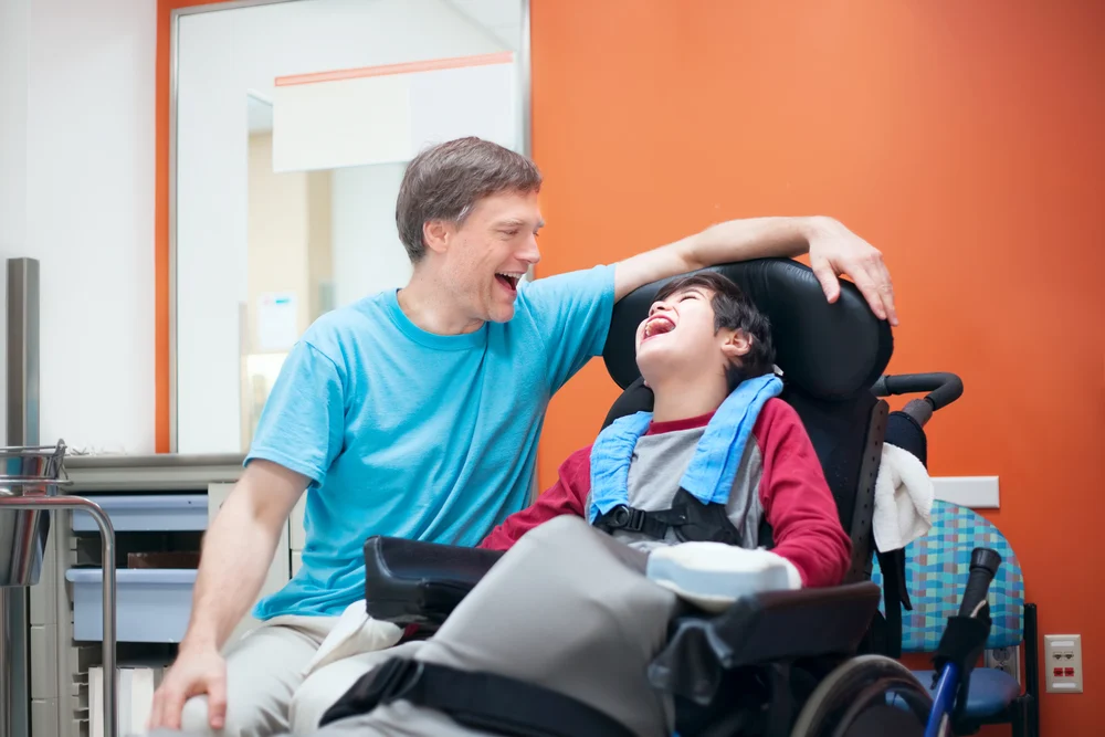 Father talking with disabled son waiting in doctor's office