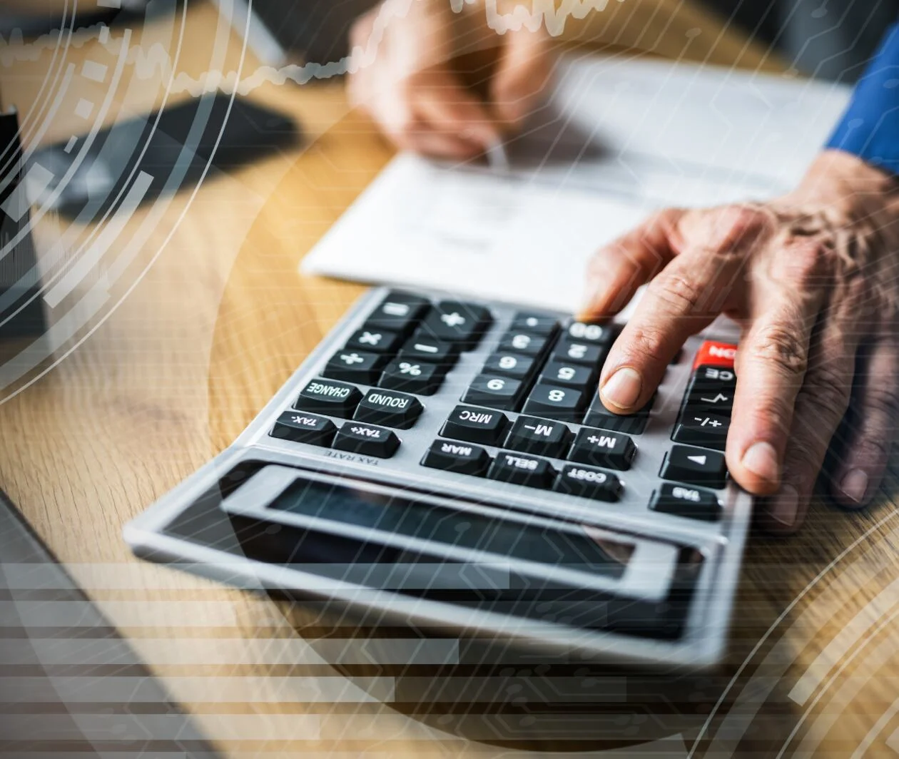 An accountant at a desk analysing a financial statement with a pen and calculator.