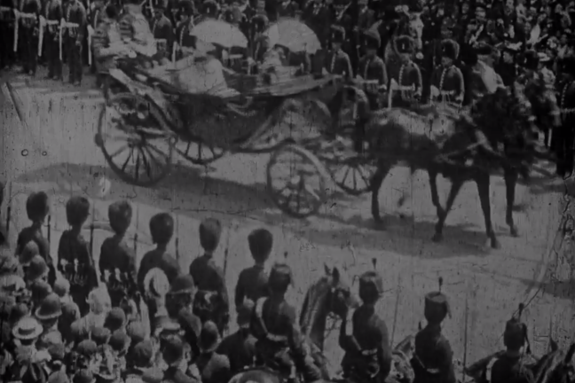 A black and white image of Queen Victoria's Diamond Jubilee. She's travelling through the crown in a carriage being pulled by horses.