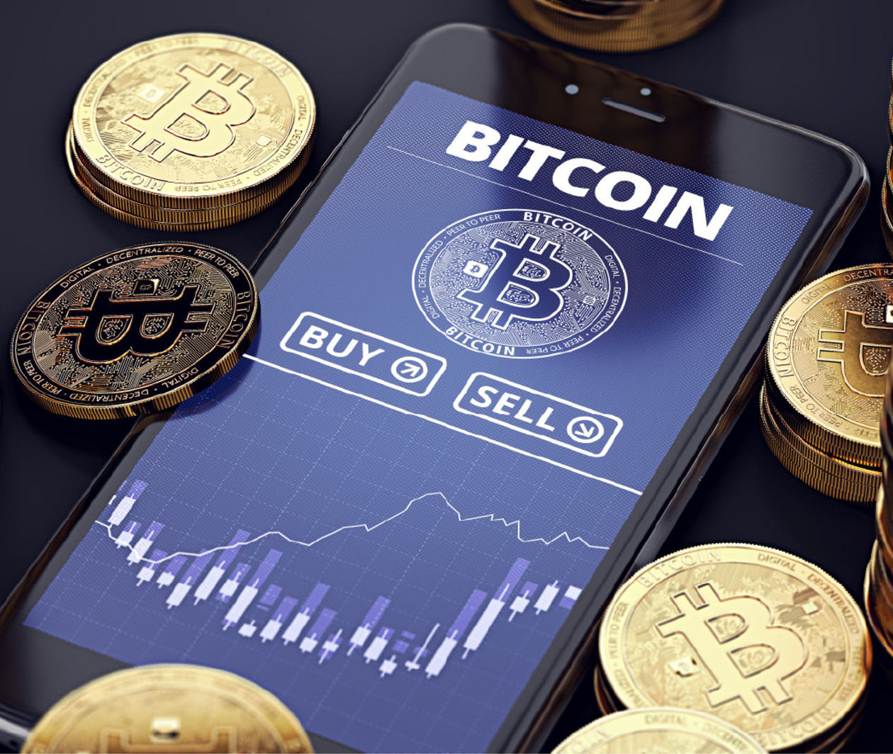 Smartphone with Bitcoin chart on-screen among piles of Bitcoins