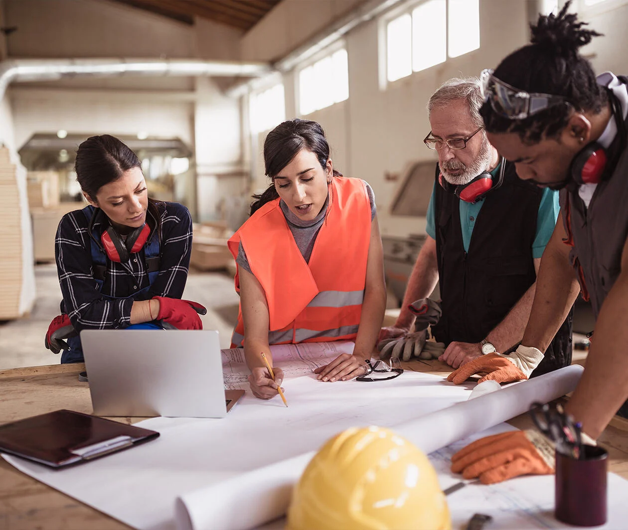 Female engineer directing her diverse team with architectural plan showing diversity and inclusion in construction and the built sector.