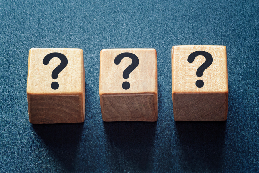 Three wooden blocks on a blue background. Each block has a question mark on it.