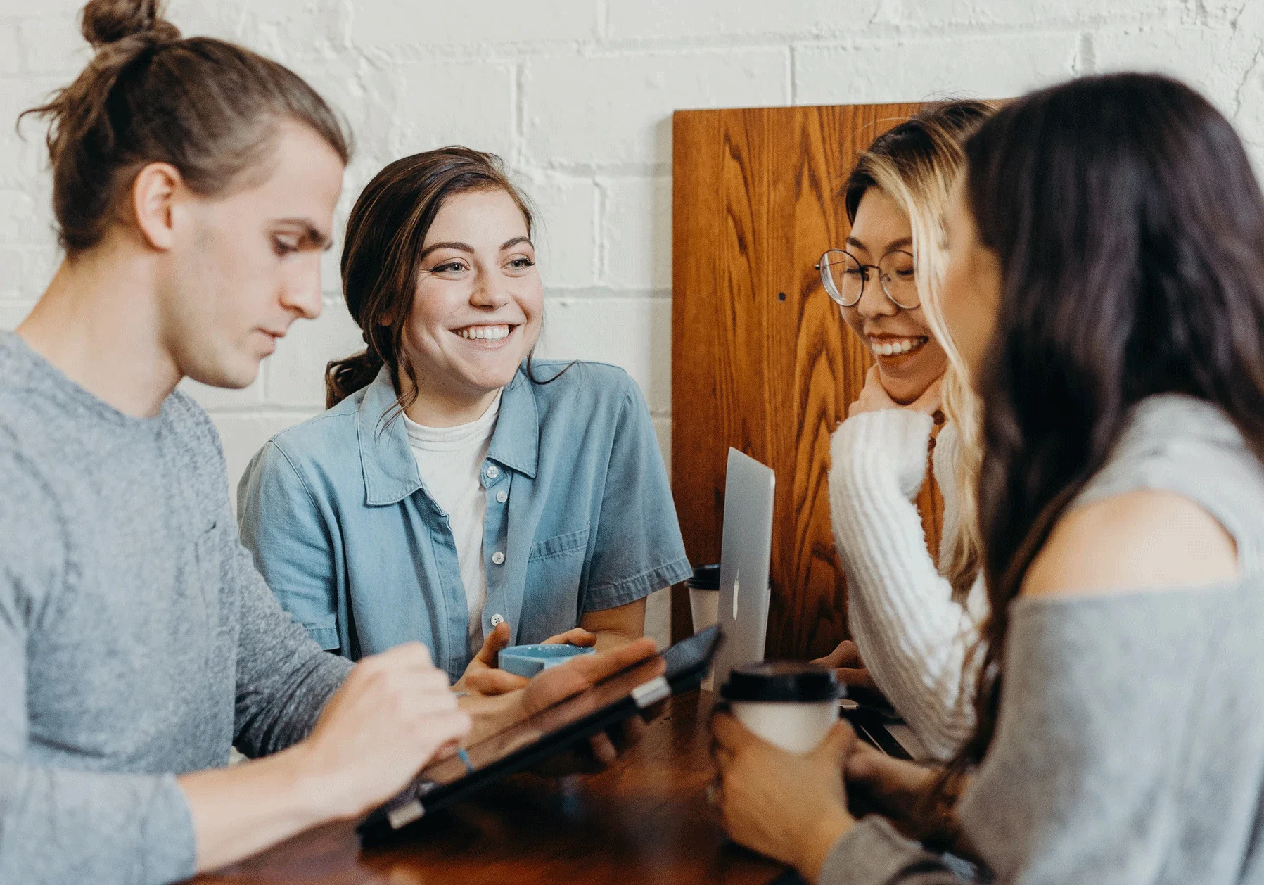 Group of students talking in a cafe with mobile devices and coffee