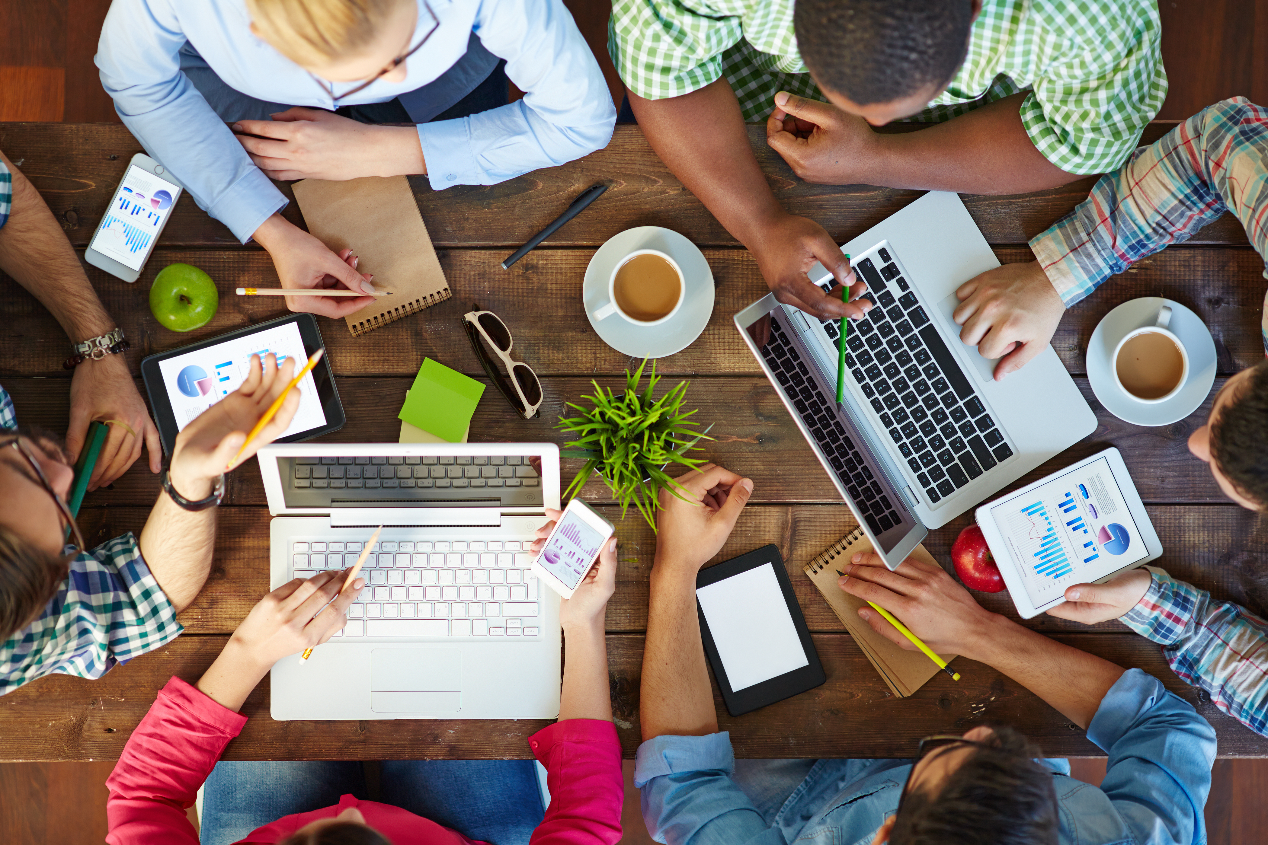 High angle view of people communicating at table with their devices