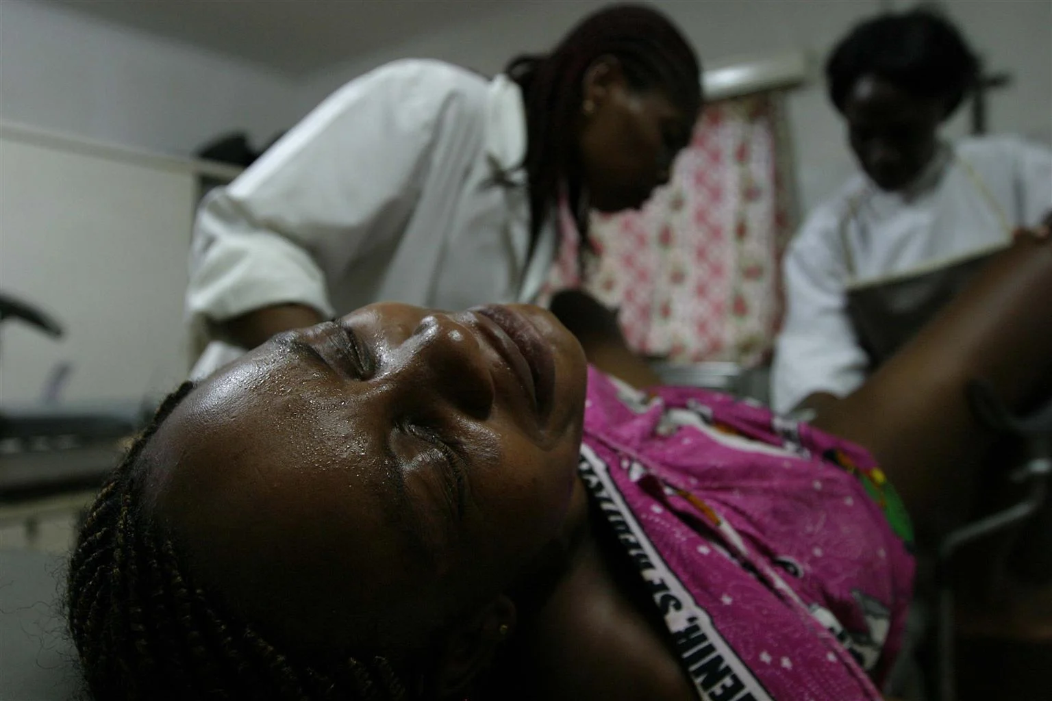 A woman gives birth in a hospital with the assistance of two female medical officers