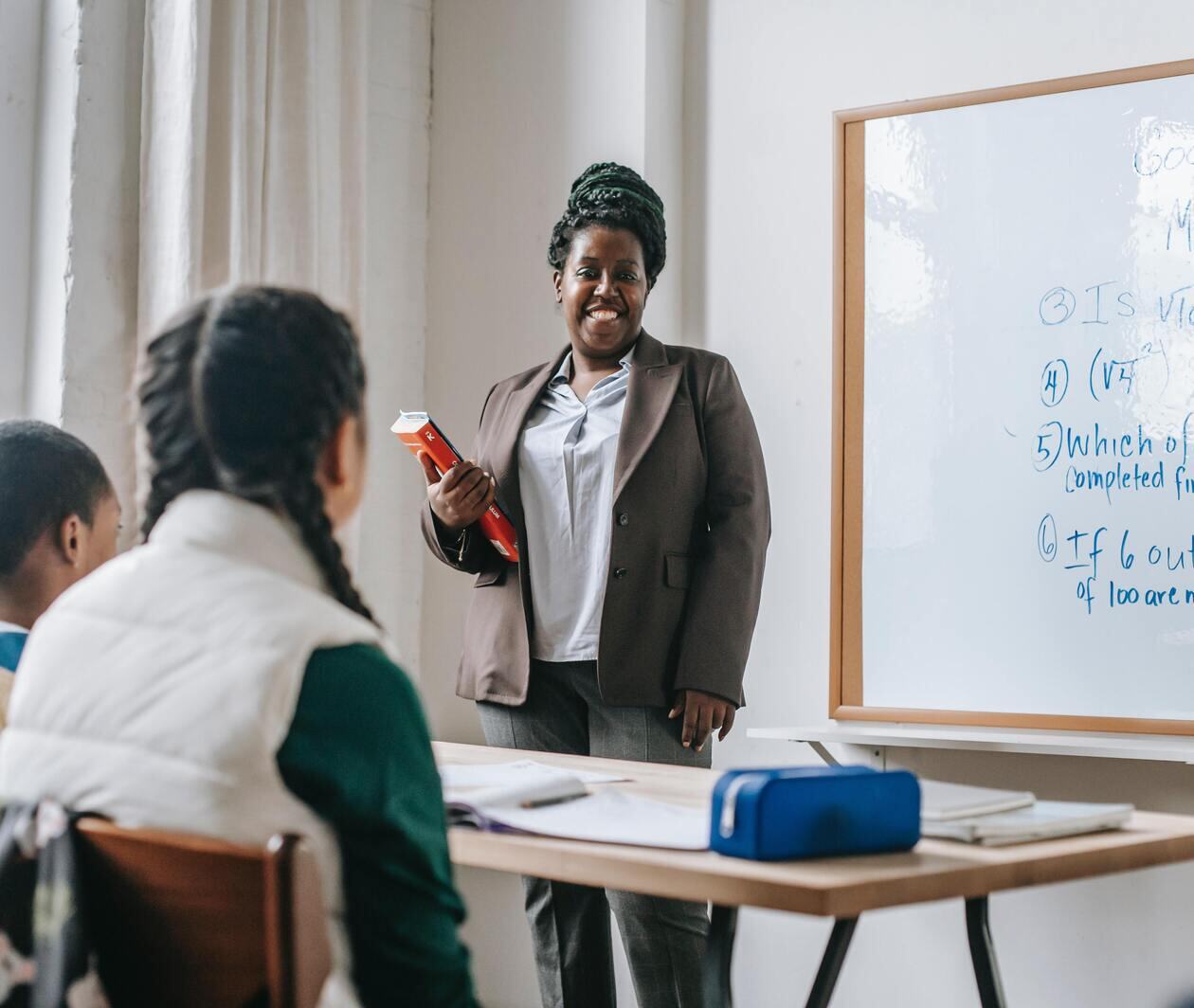 Teacher standing at the front of the classroom with a book in hand