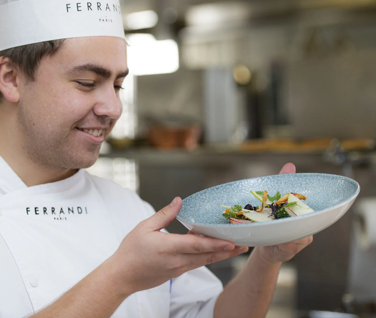 Close-up of a chef looking at a plate of French cuisine in a restaurant kitchen.