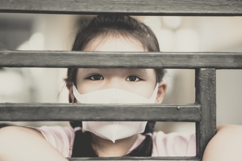 Girl wearing mask looking out of the window