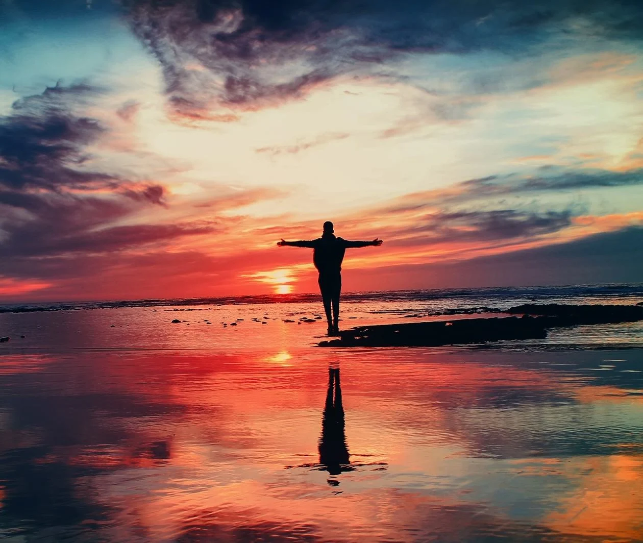 Person embracing an amazing sunset, as if looking into the future