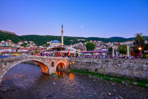 Image of a Kosovan village with a bridge, river and homes.