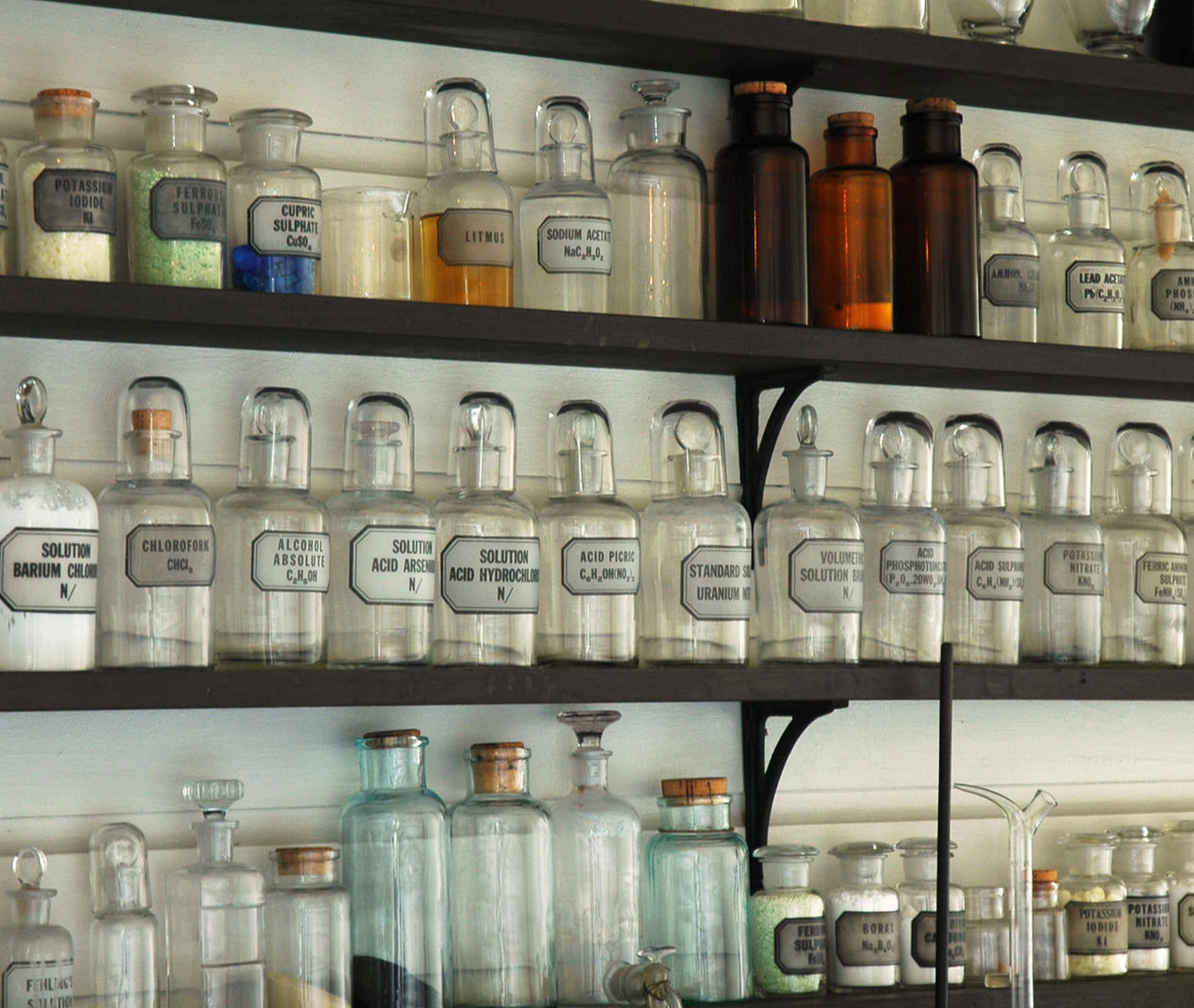 Clear old fashioned labelled bottles on a shelf in a pharmacy