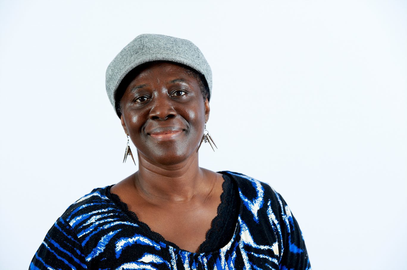 A middle aged woman smiling directly to the camera in front of a white background.