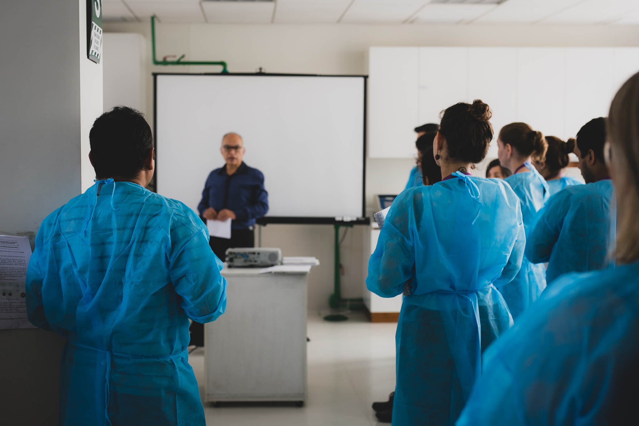 Learners in lab coats standing in preparation for a training session with an instructor