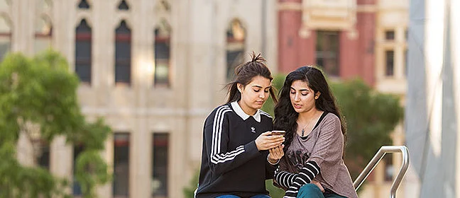 two CSU students looking at a phone on campus steps