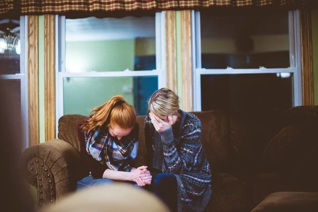 Two people on sofa comforting each other