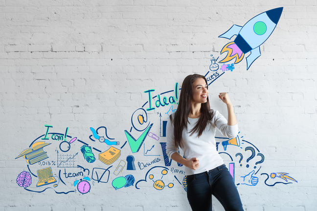 Young woman stands in front of a white wall illustrated with innovative ideas