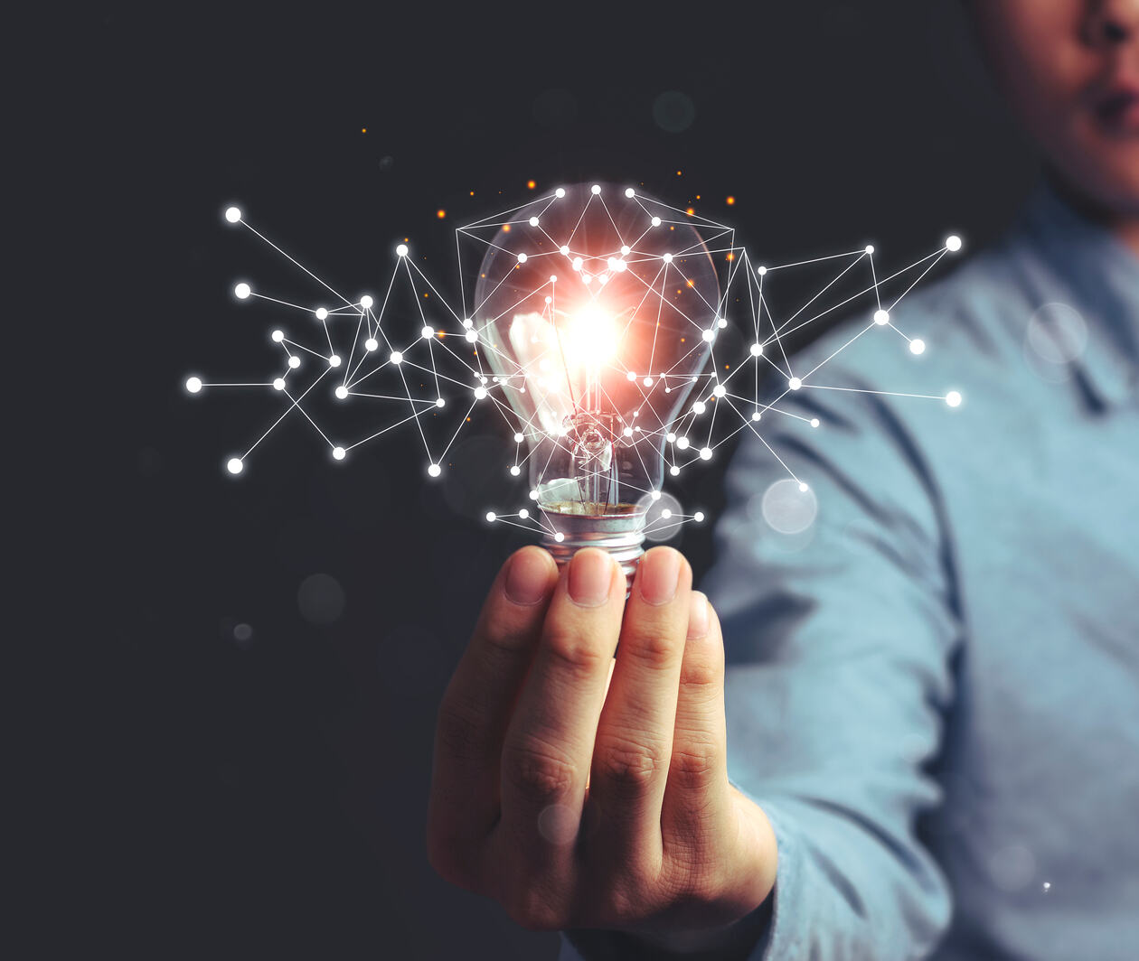 A man holds a lit lightbulb