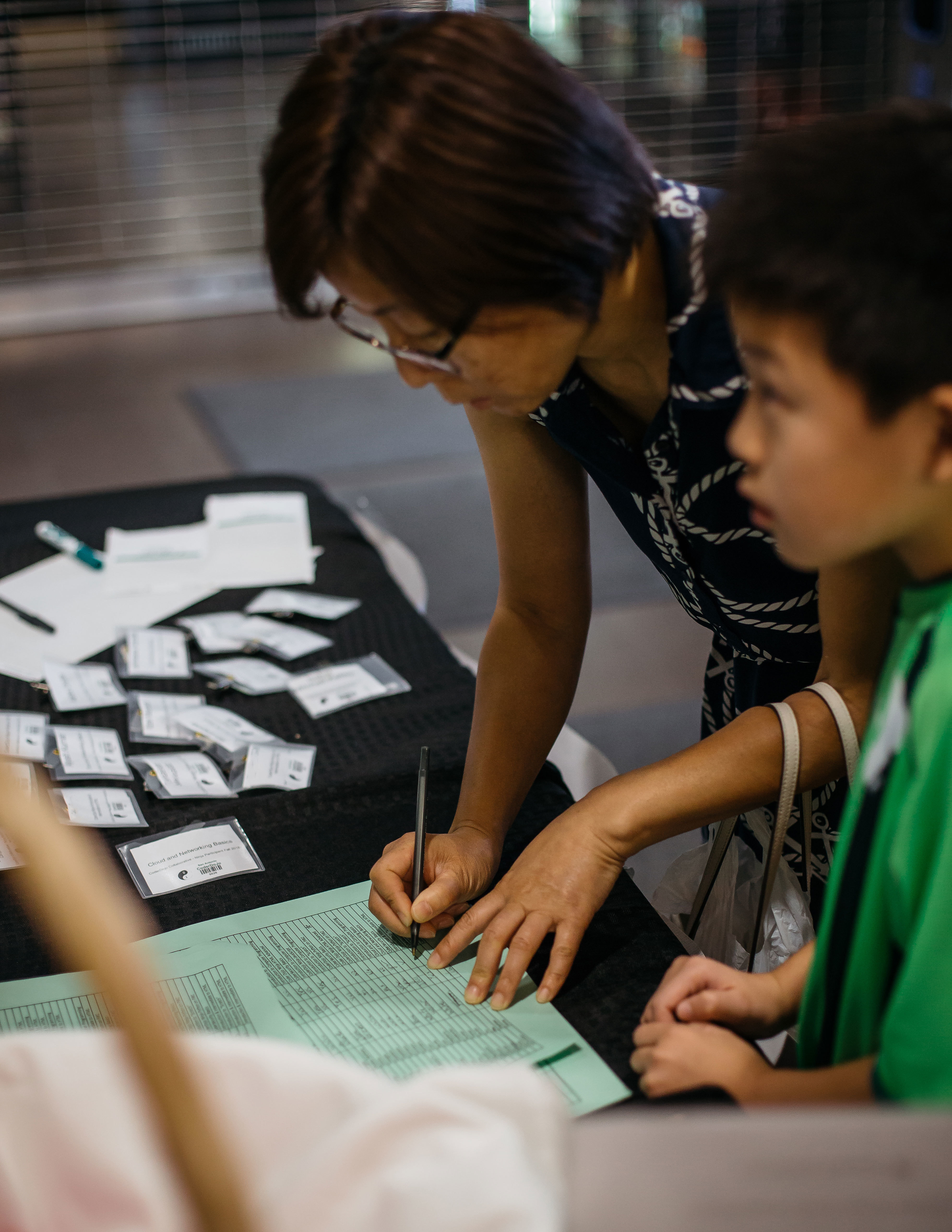 A mother and son checking into a Dojo at a registration desk full of name tags.