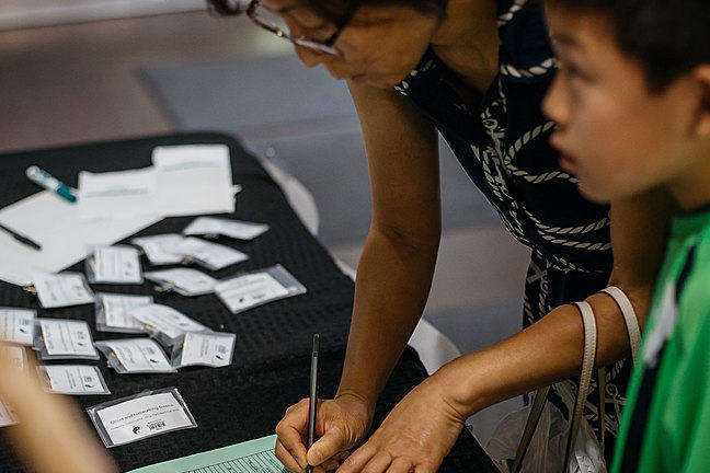 A mother and son checking into a Dojo at a registration desk full of name tags.