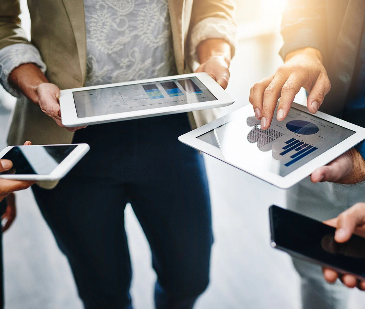 Group of people holding tablets showing data